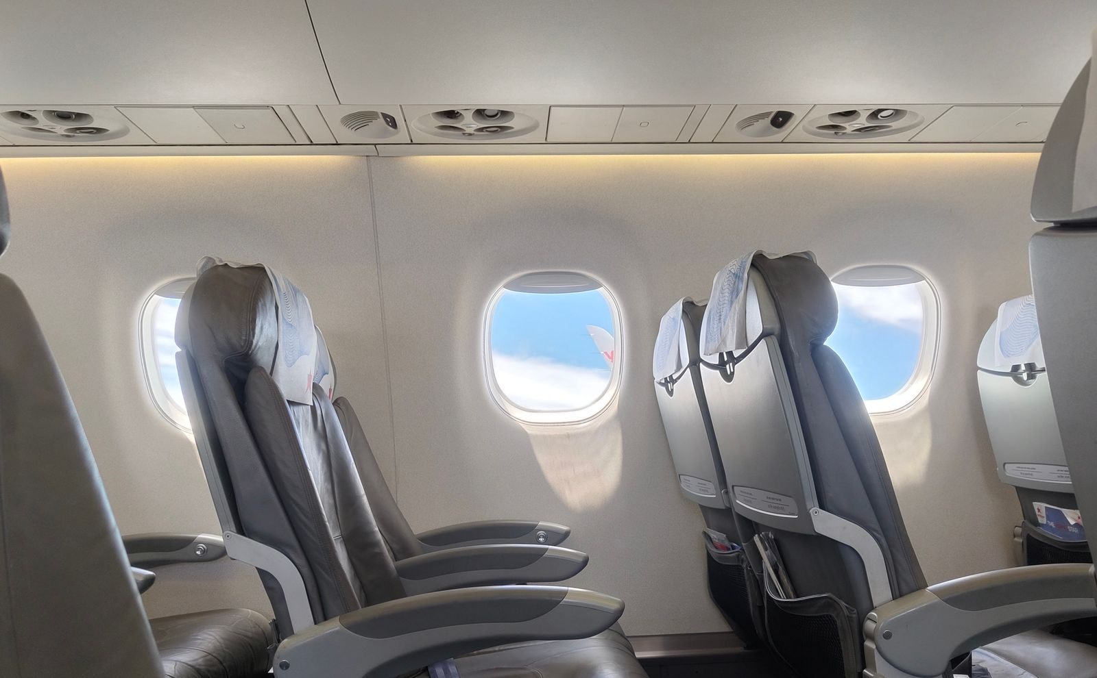 Wide leather seats beside the windows of an airliner cabin